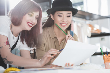 Multiethnic young fashion designers looking at sketch and discussing