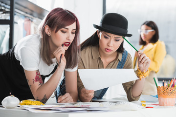 Multiethnic young fashion designers looking at sketch and discussing