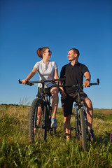 Fototapeta premium Couple of cyclists riding bicycles in meadow