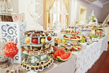 Gorgeous-looking wedding table with various beverages, delicious dishes, fruits and decorations.