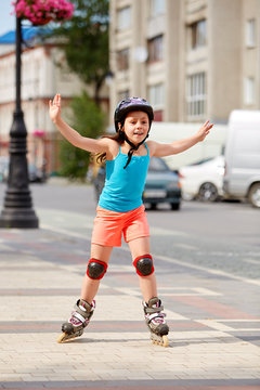 Cute little girl learning to roller skate outdoors on beautiful summer day
