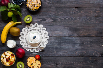 Healthy breakfast, cereal with yogurt, strawberries, blueberry, apple, banana, on rustic wooden.  Top view
