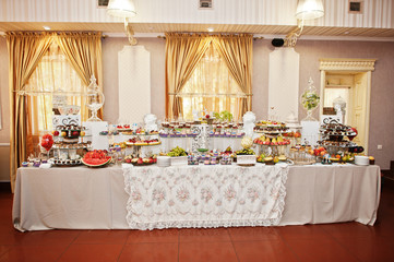 Gorgeous-looking wedding table with various beverages, delicious dishes, fruits and decorations.