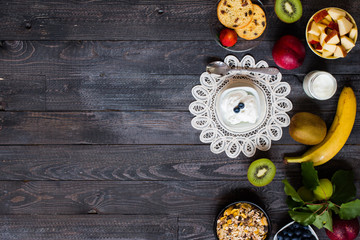 Healthy breakfast, cereal with yogurt, strawberries, blueberry, apple, banana, on rustic wooden.  Top view