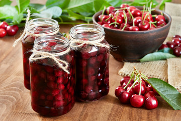 Cherry jam on wooden background in the jars