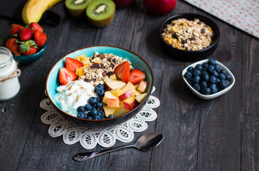 Healthy breakfast, cereal with yogurt, strawberries, blueberry, apple, banana, on rustic wooden.  Top view