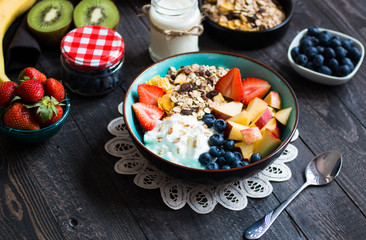 Healthy breakfast, cereal with yogurt, strawberries, blueberry, apple, banana, on rustic wooden.  Top view