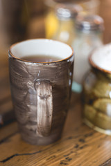 Clay brown cup of dark filtered coffee on wooden rustic table