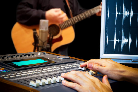 sound engineer hands working on digital sound mixer for acoustic guitar recording in music studio