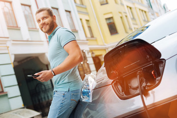 Handsome man using tablet while car being charged