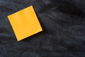 Orange stick notes on blackboard background. Copyspace.

