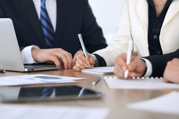Group of businesspeople or lawyers discussing contract papers and financial figures while sitting at the table. Close-up of human hands at meeting or negotiations. Success and communication concept