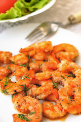 Fried tiger prawns with herbs and spices on a white plate.