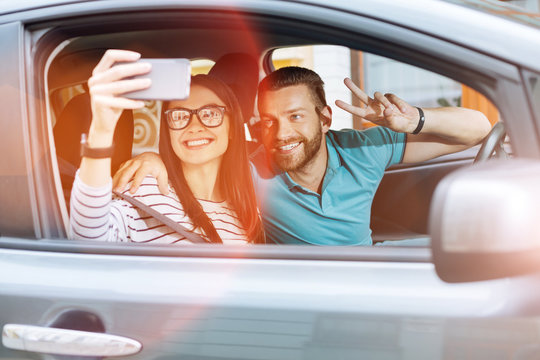 Beautiful young couple making selfies in a car