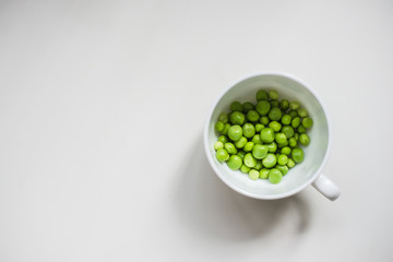 Cup with green peas on a white background