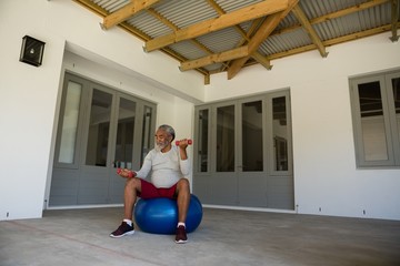 Man exercising with dumbbells on exercise ball 