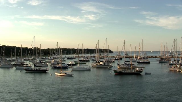 Sailboats moored and anchored in Vineyard Haven in late afternoon sun from deck of ferry boat as it departs from dock