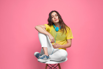 Girl with earphones sitting on chair posing