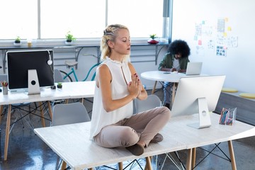 Female executives doing yoga in office