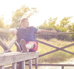 Man sitting on a bench by the ocean/lake on a sunny day. Summer/autumn. - 163010924