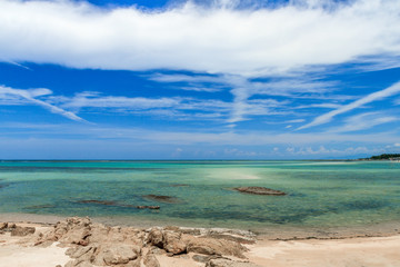 Beautiful wild beach with green water under the blue sky with white clouds 