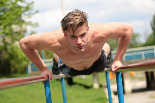 Man with confident face performs on parallel bars