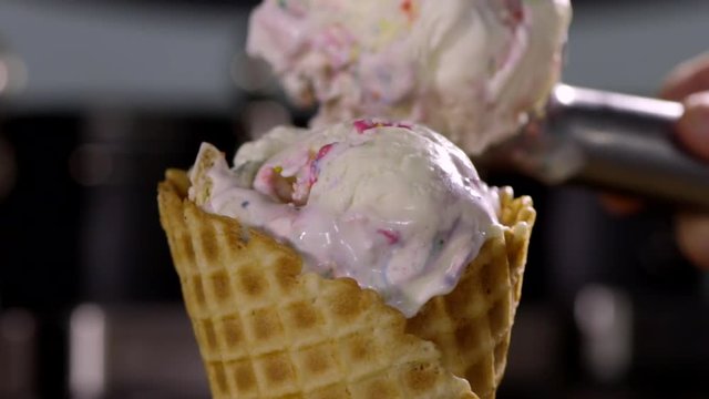 Closeup Of Waffle Cone, Woman Adds Another Scoop Of Colorful Ice Cream On Top