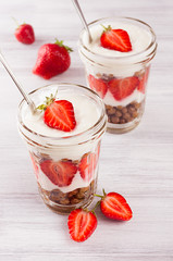 Breakfast with strawberry and chocolate balls corn flakes on white wood board.