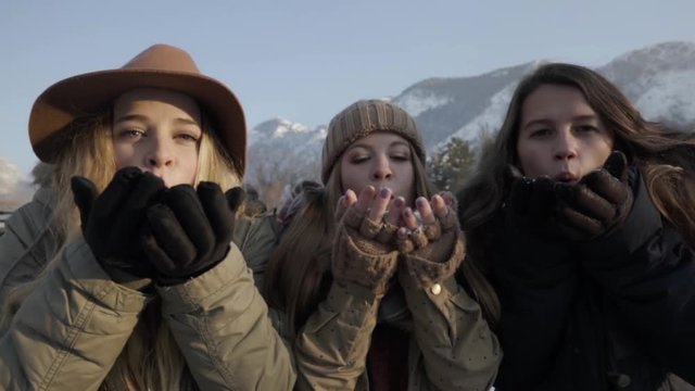 Slow Motion Closeup Of Group Of Teen Girls Blowing Handfuls Of Snow At Camera Then Smiling And Laughing