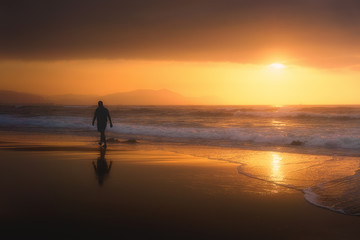 Fototapeta na wymiar lonely person walking on beach at sunset