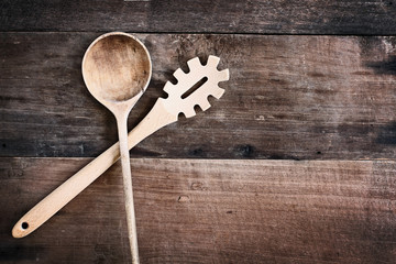 High angle view of a old empty wood spoon and spaghetti fork over a rustic wooden background. Available copy space for text.