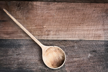High angle view of a old empty wood spoon over a rustic wooden background. Available copy space for...