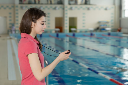 Swim coach looking at stopwatch near poolside at the leisure center