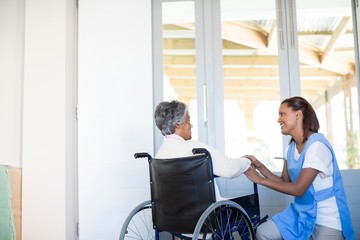 Female doctor interacting with senior woman on wheelchair