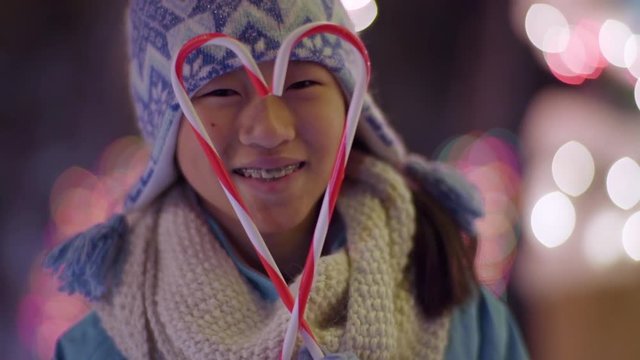 Little Girl Makes A Heart Shape With Candy Canes, She Smiles With Holiday Joy (Slow Motion)