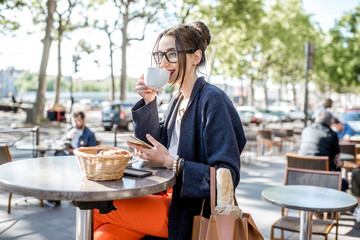 Young woman having a breakfast with coffee and croissant sitting outdoors at the french cafe in...