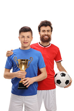 Teenage soccer player holding a golden trophy with his father