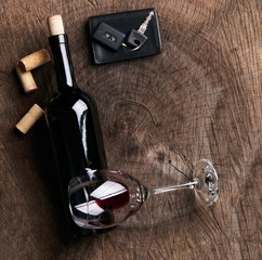 Top view of a Car key on the wooden bar with glass of wine alcohol and empty bottle of red dry...