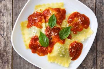 Ravioli with tomato sauce and basil on wooden table
