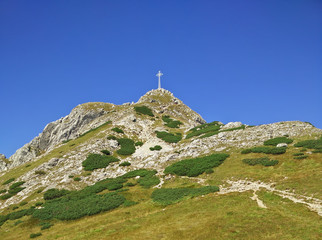 Cross on the Giewont in Tatra Mountains in Poland with a blue sky in the background