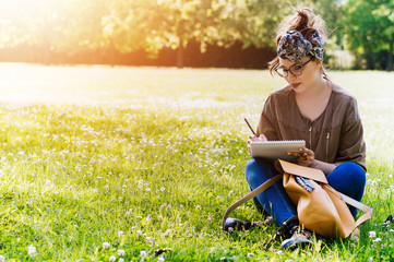 Girl on nature writing in a notebook