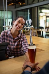 Happy barmaid serving drink to man