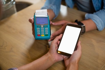 Cropped hands of customer making payment at restraurant