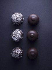 Danish floedeboller (chocolate covered marshmallows), some with desiccated coconut, isolated on black background