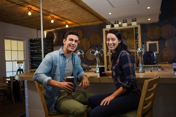 Portrait of smiling friends enjoying drinks at bar