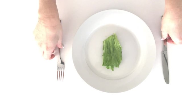 Eating disorder. Cropped image of woman hands eating piece of lettuce. Copy space