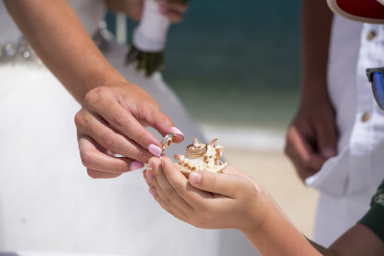 Bride is holding in her arm golden wedding ring on the caribbean seashore in summer sunny day