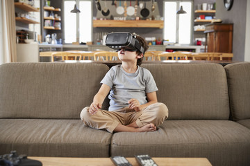 Obraz premium Boy Sitting On Sofa Wearing Virtual Reality Headset