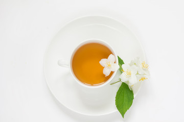 Jasmine flowers and cup of green tea on white background. Top view and concept.