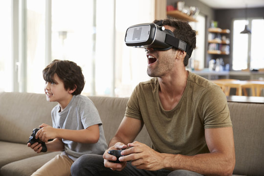 Father And Son Play Computer Game Using Virtual Reality Headset - Powered by Adobe